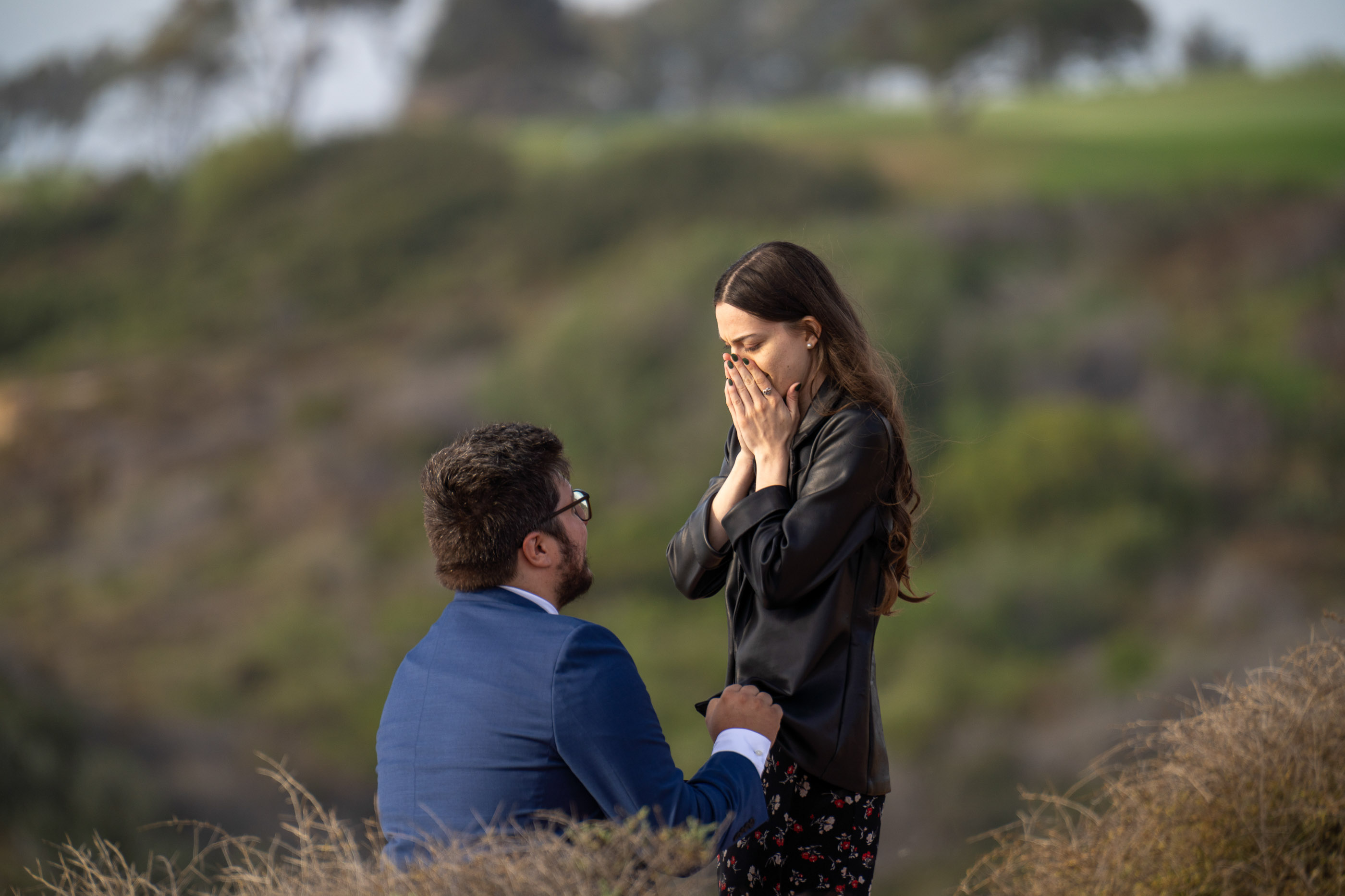 Couple sharing an emotional moment during a surprise proposal outdoors
