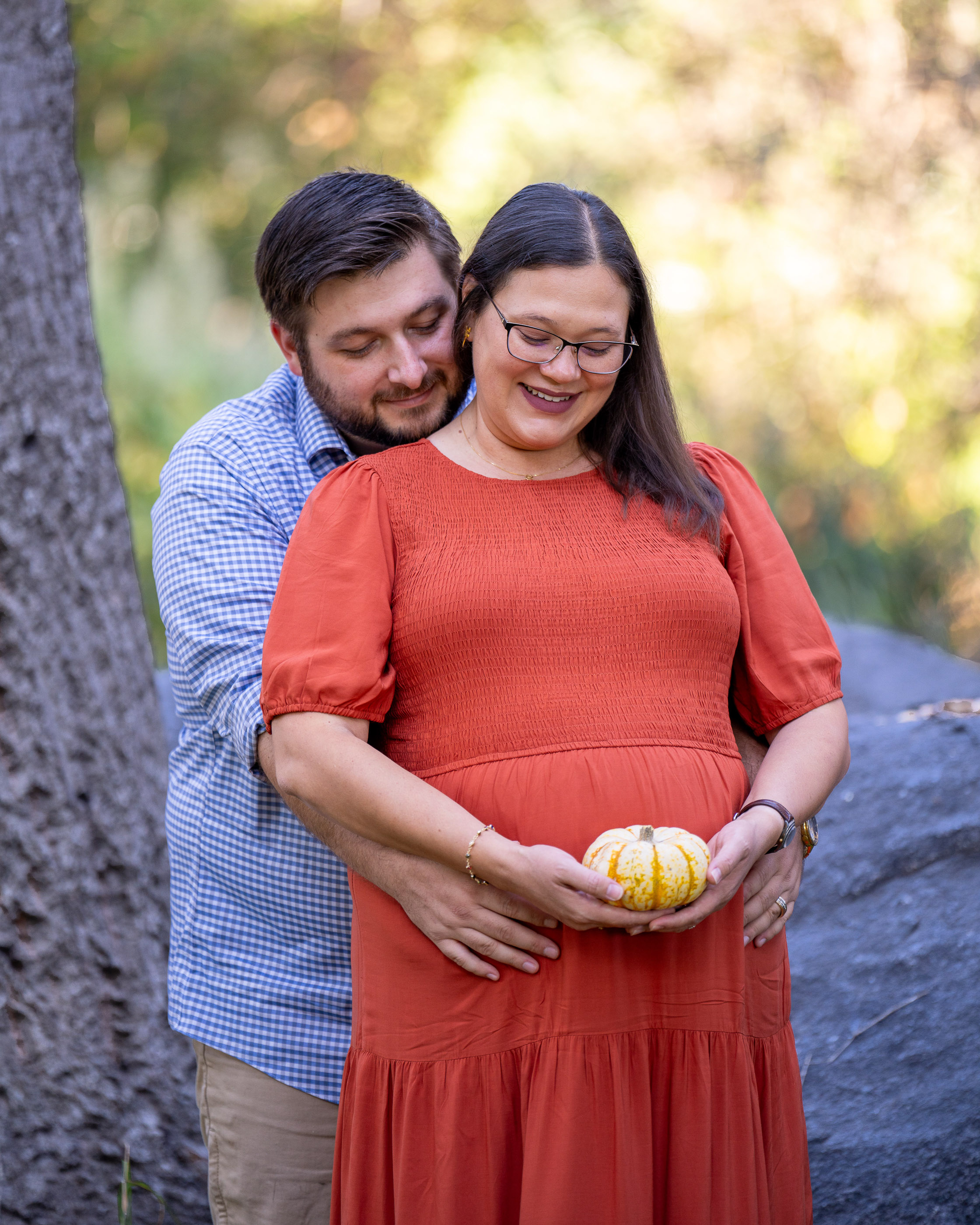 Pregnant woman smiling while her partner embraces her from behind